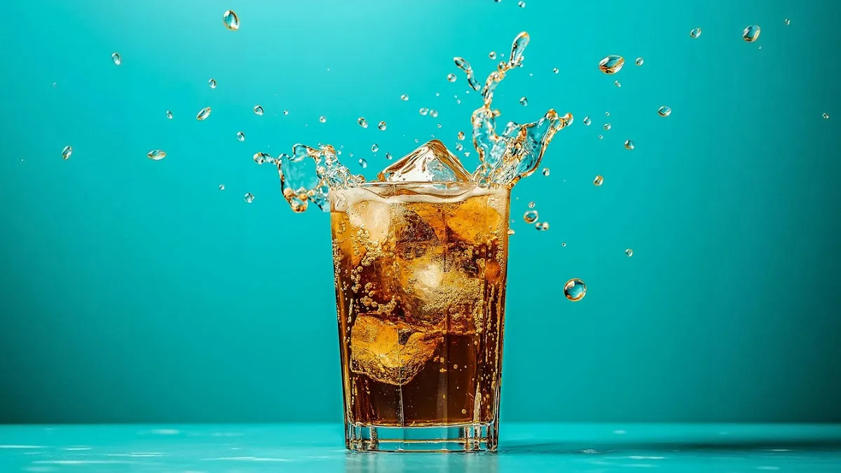 Glass with Zova fizzy drink and ice inside it