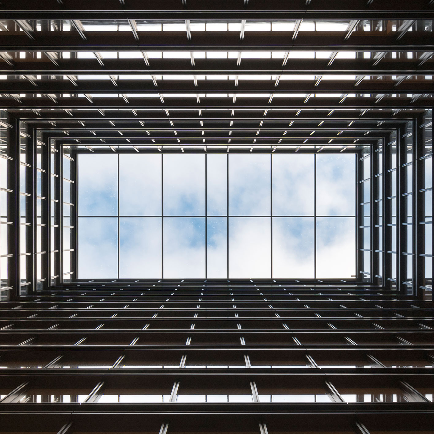Blick nach oben in die gläserne Dachkonstruktion eines architektonisch klaren Gebäudes von Nigel Young.