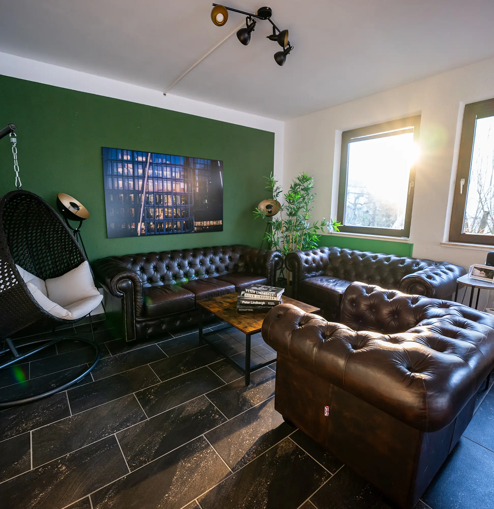 StudioDarmstadt Lounge mit gemuetlichen Chesterfield-Style Sofas und einem Coffee-Table mit Fotobüchern