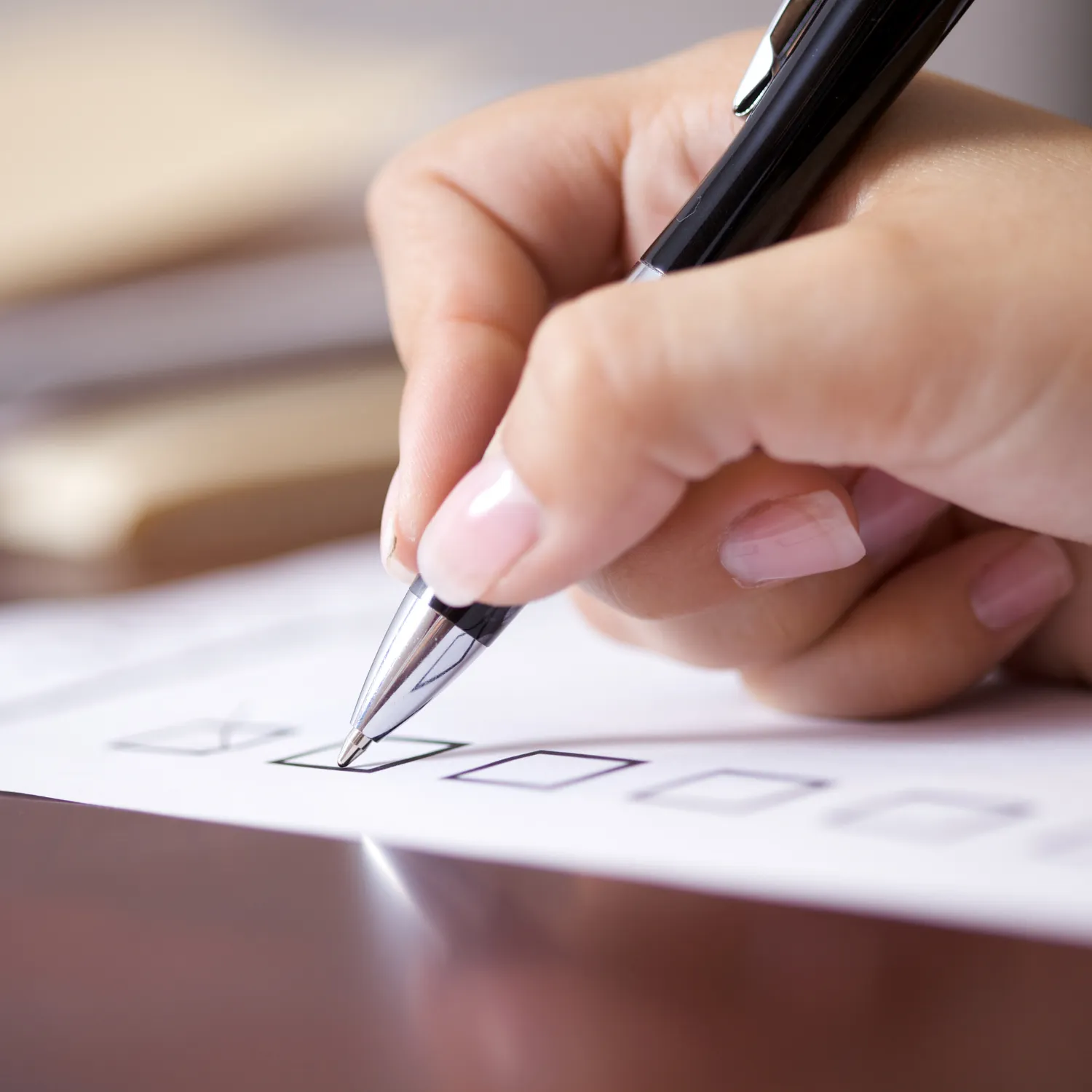 Close-up of hand marking a checkbox on a paper form with a pen.