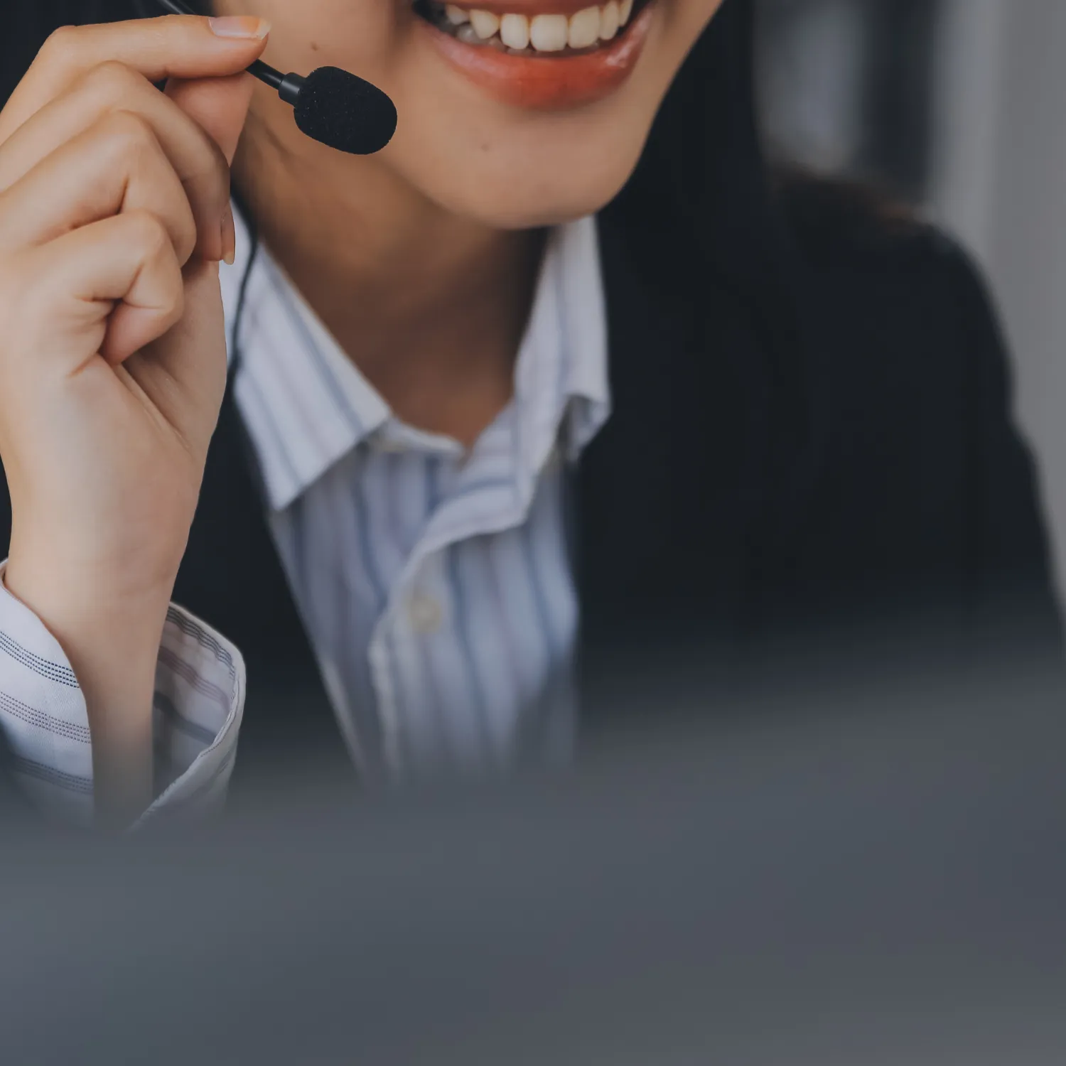 Close-up of a smiling woman wearing a headset and speaking into a microphone.