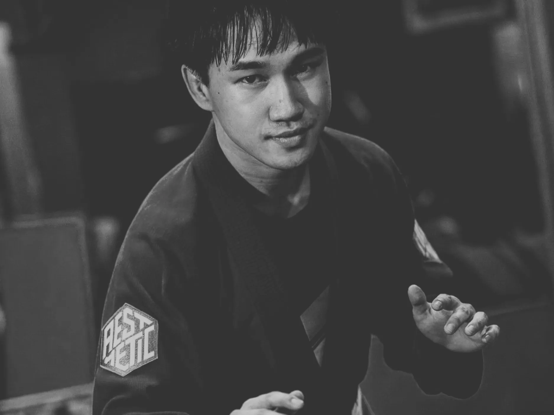 Young man in a martial arts gi with a focused expression, posing with hands raised in a defensive stance.