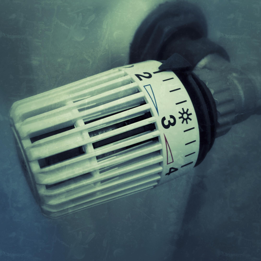 Close-up van een witte thermostaatknop op een radiator met instellingen van 1 tot 4 en een zonnesymbool bij 3.