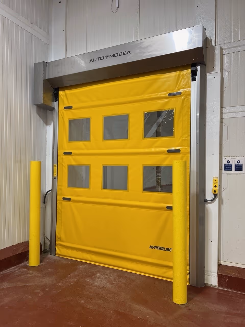 Bright yellow industrial roll-up door with six small rectangular windows and metal frame in a warehouse.