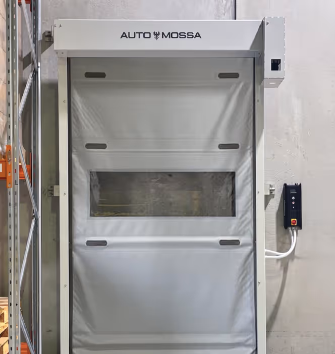 White industrial automatic roll-up door with a clear window panel, labelled 'AUTO MOSSA' at the top, installed in a warehouse setting.