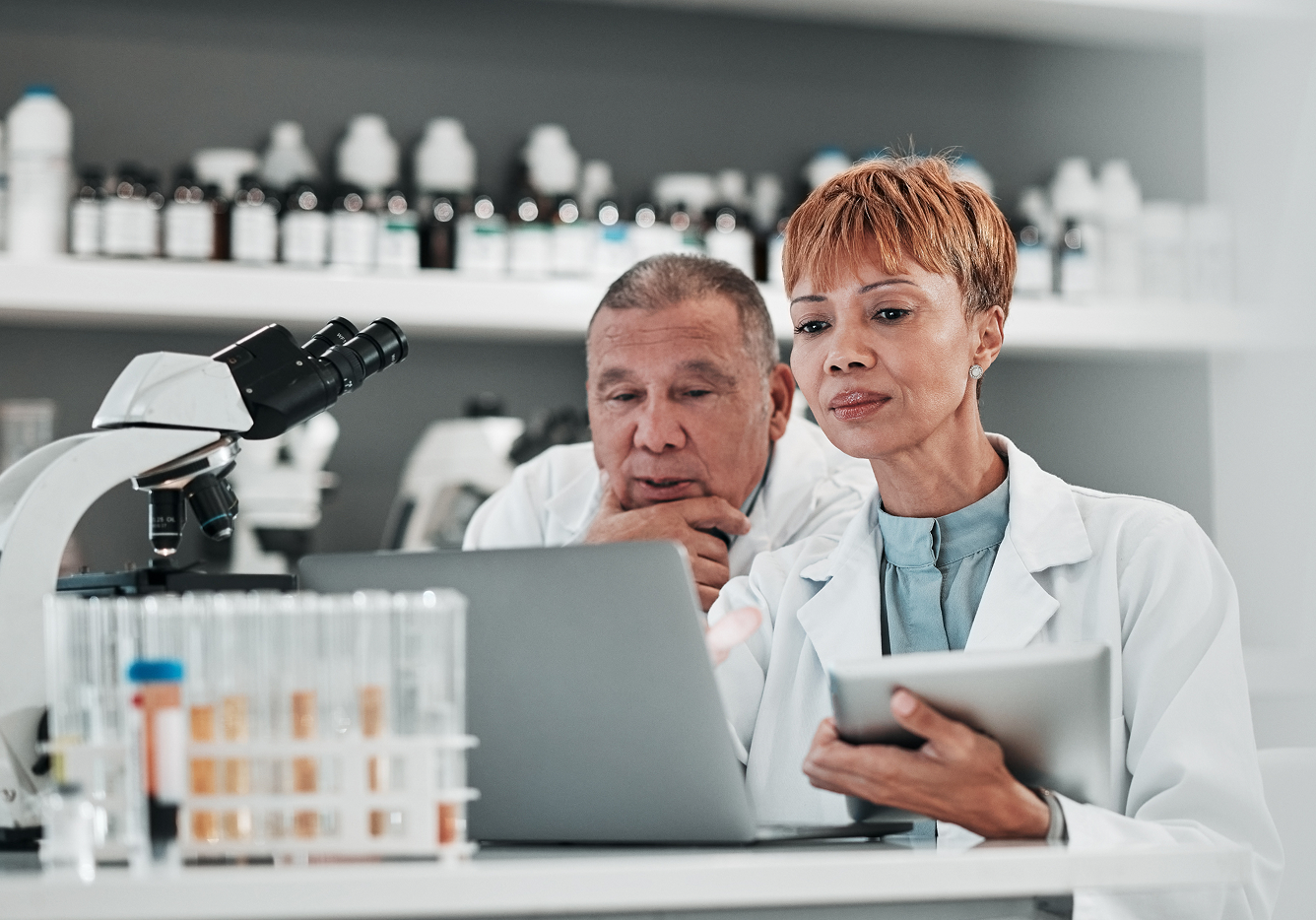 Two quality and compliance managers collaboratively reviewing digital HACCP records and comparison data on a food safety software platform screen.