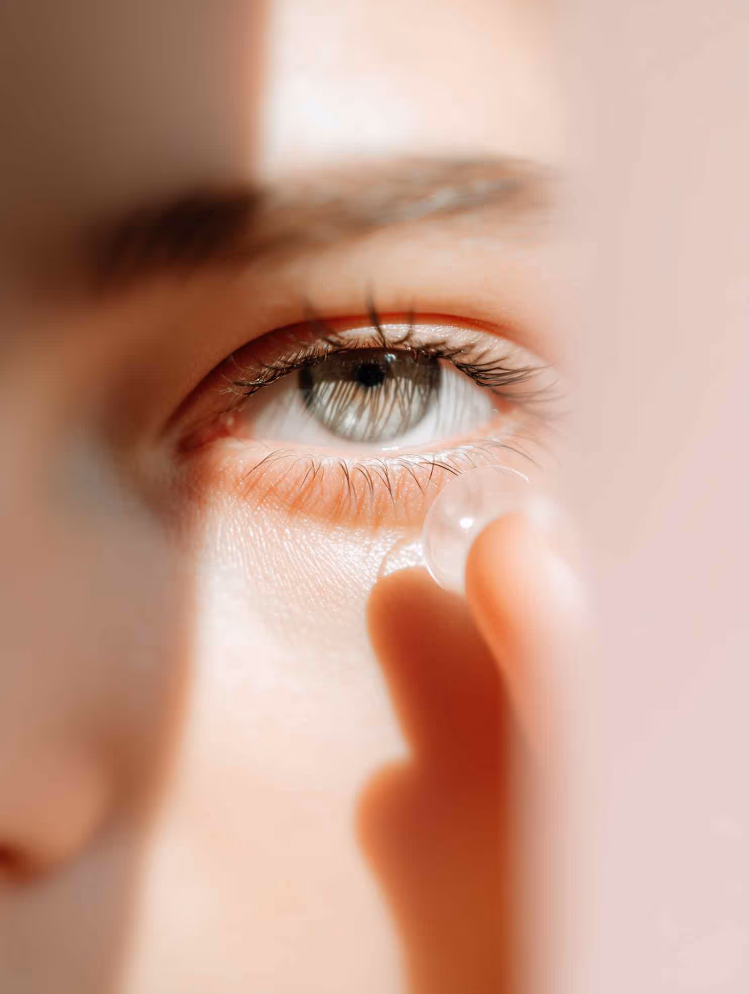 Nahaufnahme eines Auges, in das eine Hand eine Kontaktlinse einsetzt.