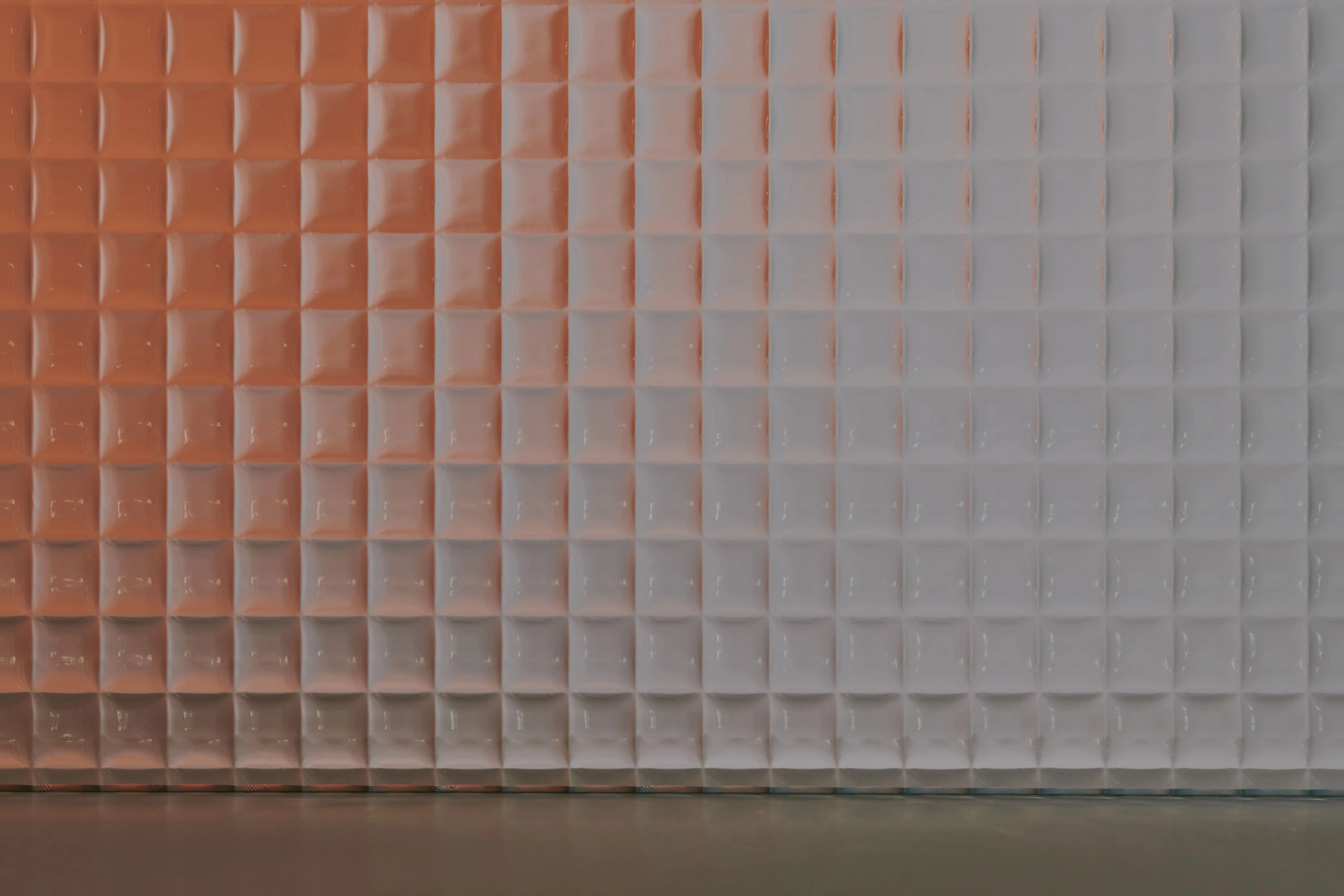 Wall featuring a grid of square, three-dimensional panels with a gradient orange to white lighting effect.