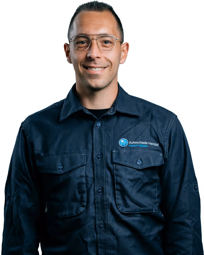 Man met korte donkere haar en een bril die een donkerblauw overhemd draagt met een geborduurd logo van Autoschade Herstel.