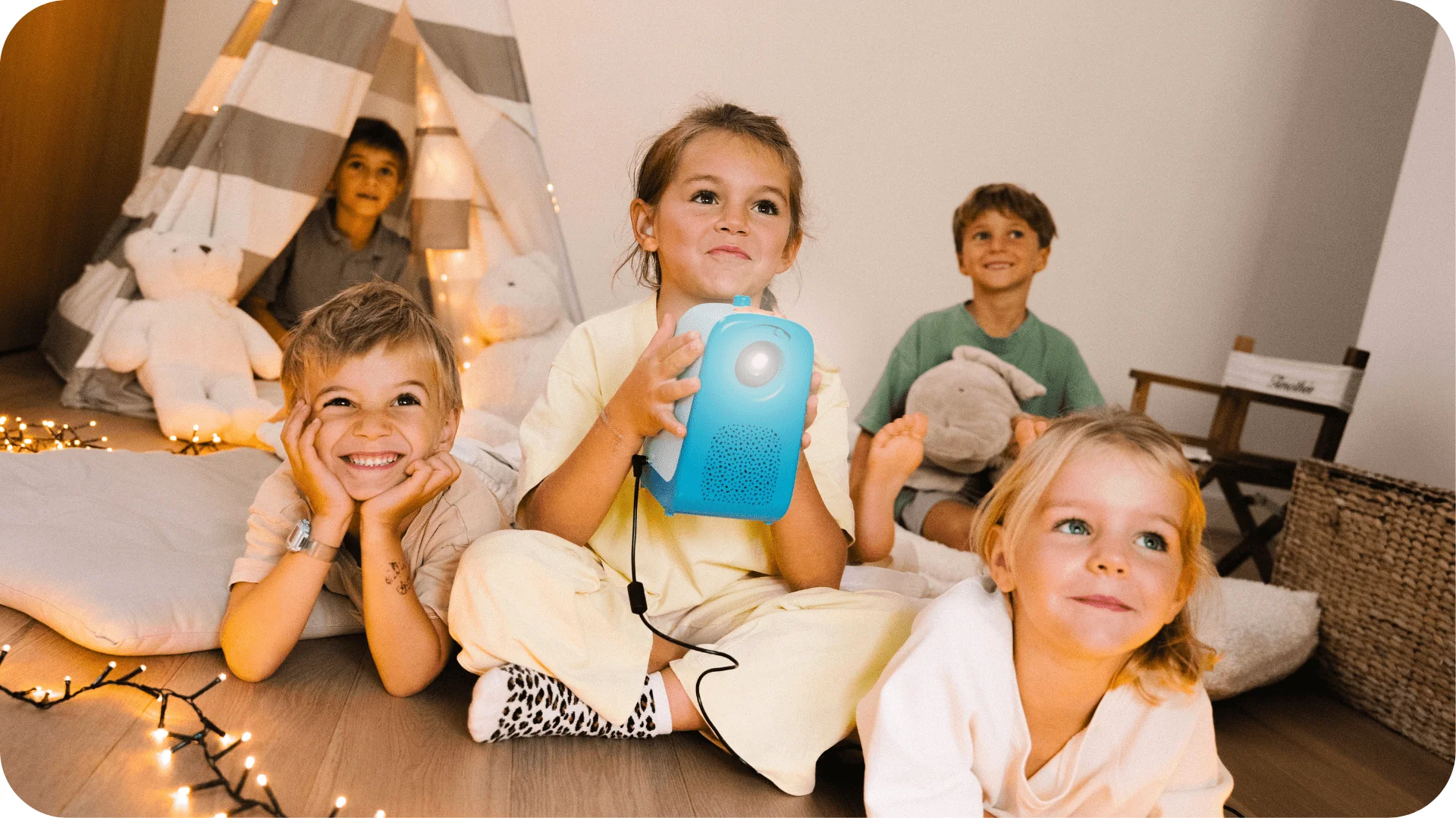 Un groupe d'enfants regardent ce qui est projeté au mur en souriant grâce au projecteur de la marque Tikino.