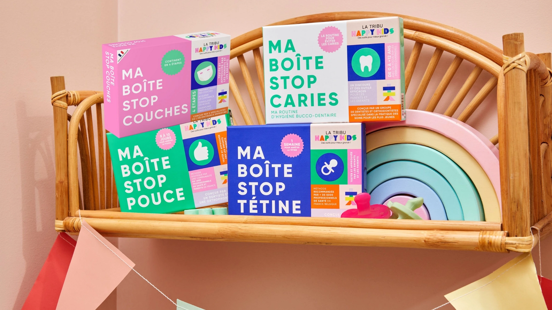Boîtes colorées de la marque La Tribu Happy Kids de soins pour bébés, disposées sur une étagère en bois, couleurs pastels.