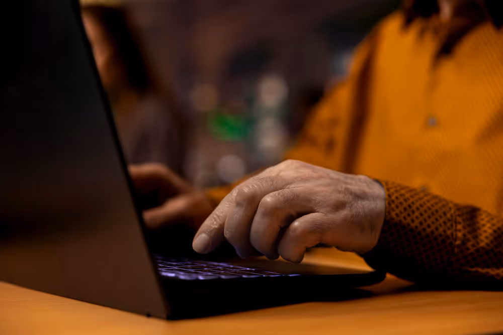 Close up of person wearing orange short typing on a black laptop