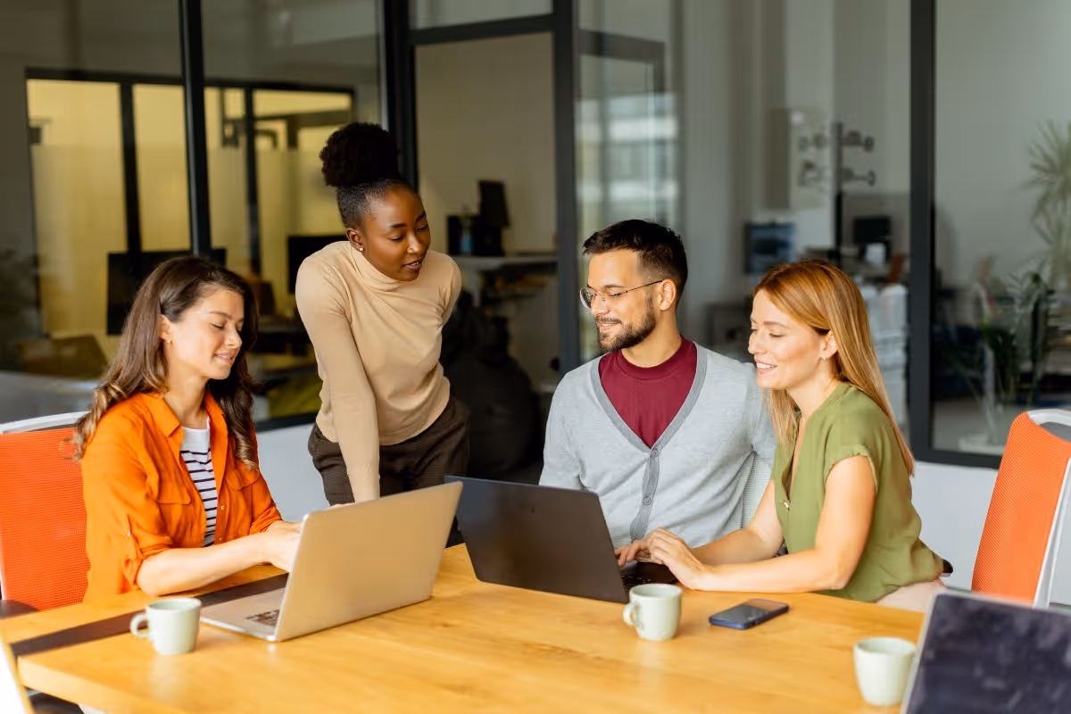 Group of people sitting around a table in a modern, colourful office.