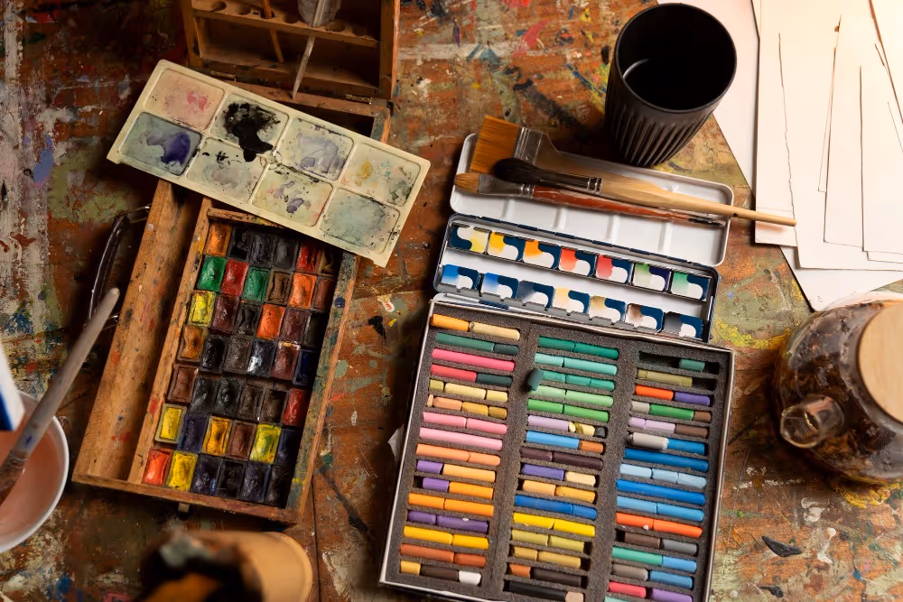 An artist table covered with paint, water colours and chalk