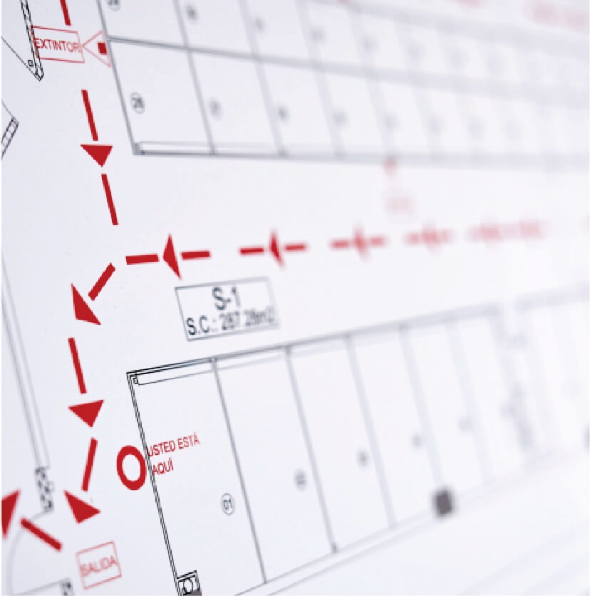 Close-up of a building floor plan with red dashed directional arrows and emergency route markings.
