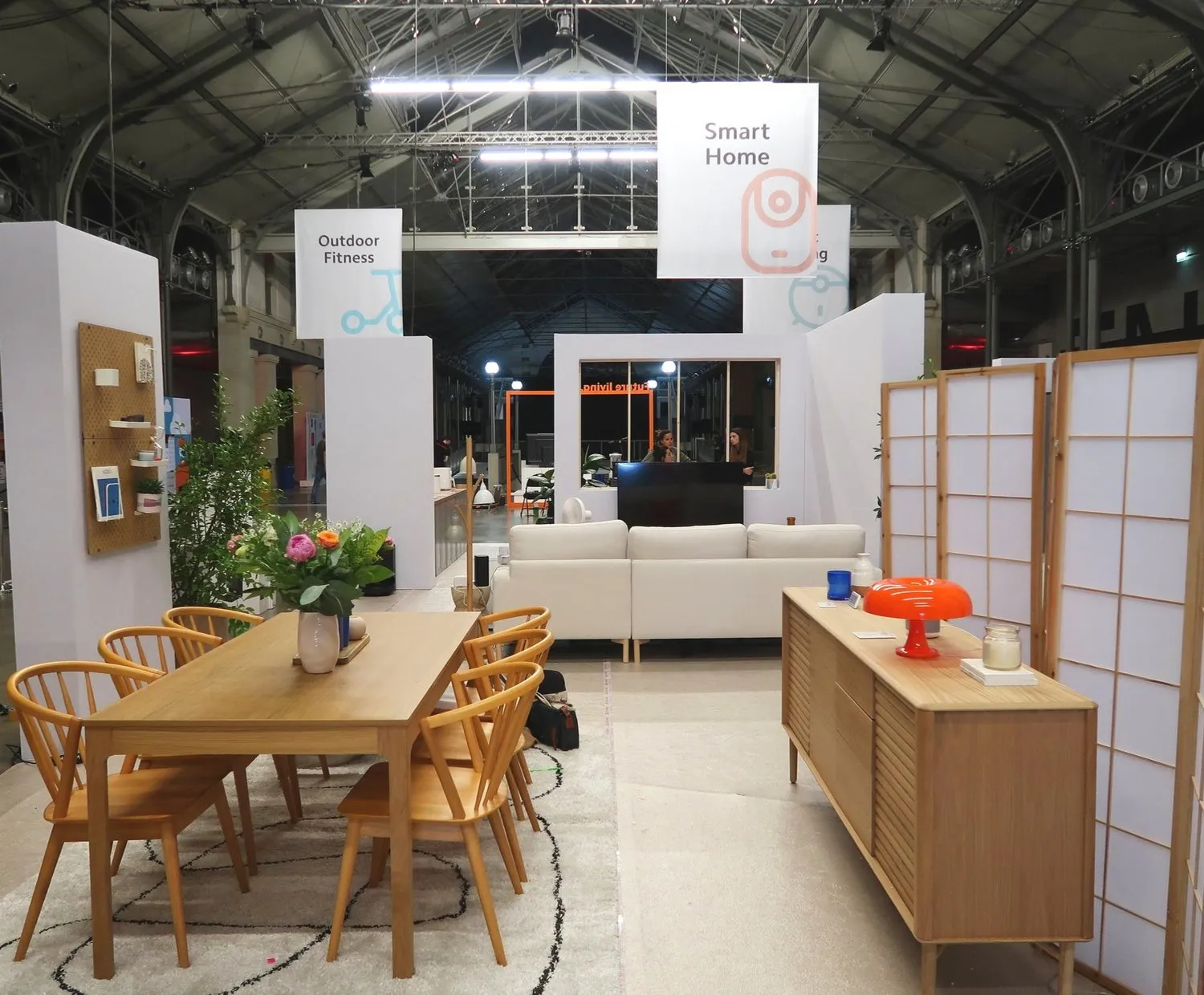 Sculptures of soccer players painted orange displayed on pedestals at an outdoor event with the Arc de Triomphe in the background.