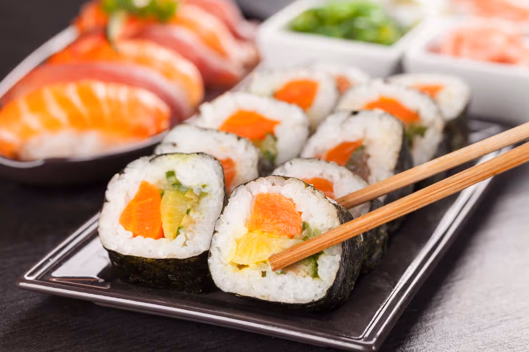 10 sushi pieces being grabbed with a pair of chopsticks