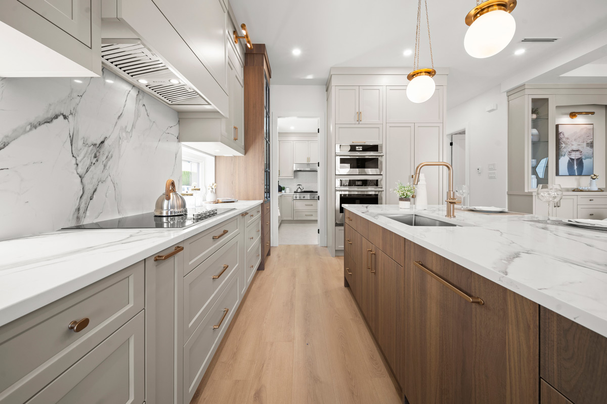 Built by Asthan Homes in Burnaby, BC, kitchen with marble countertops, wooden cabinets, pendant lights, and stainless steel appliances.