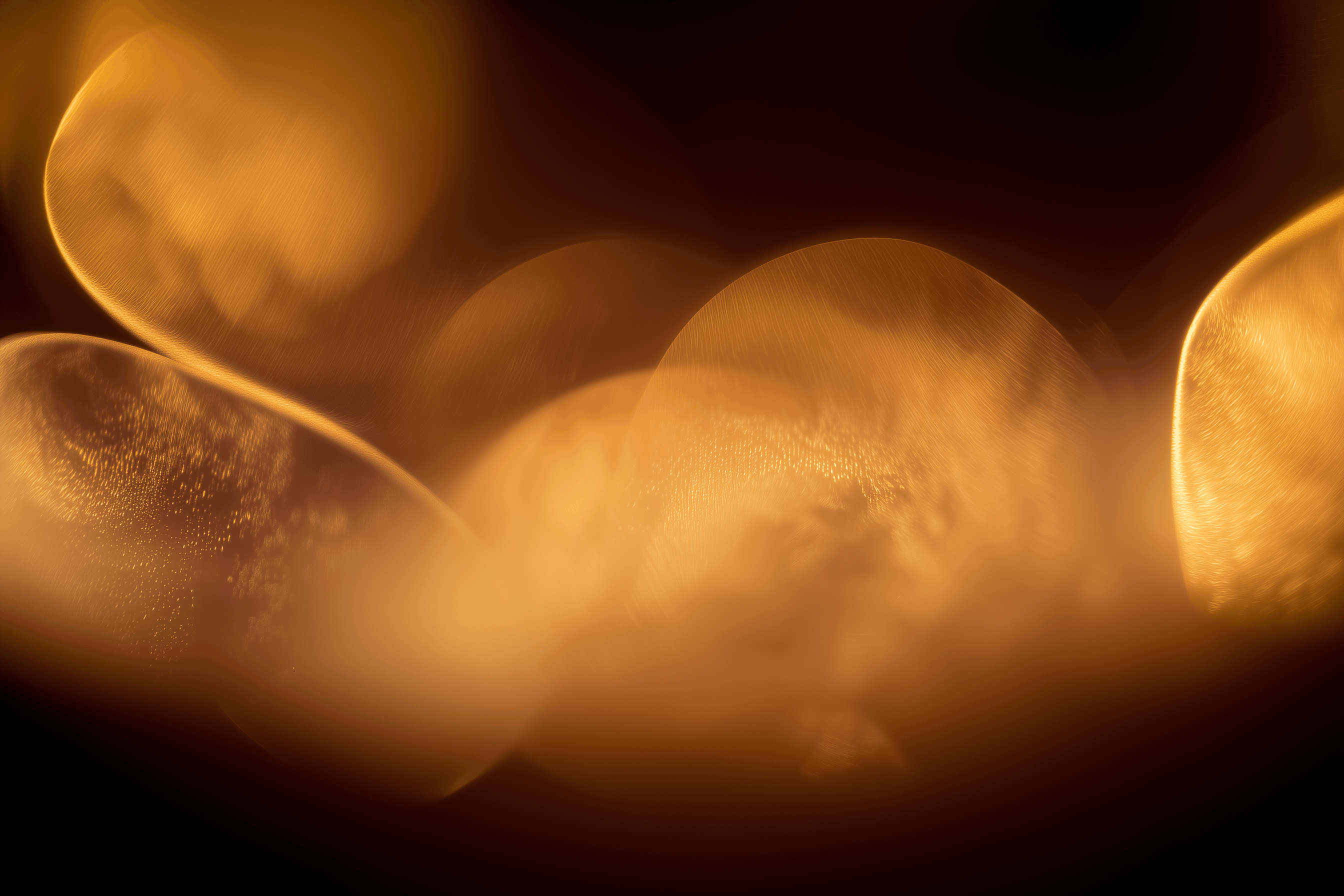 Close-up of golden bubbles clustered together on a dark background.