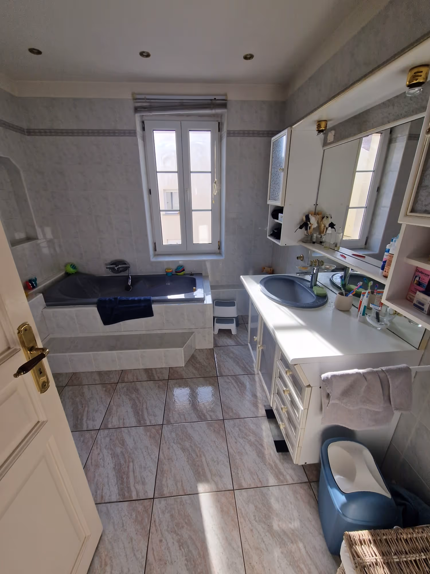 Photo avant chantier, Pièce en cours de rénovation avec sol pelé et sacs blancs posés près d'une grande fenêtre ouverte.