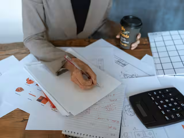 Persona revisando documentos financieros en un escritorio con taza de café