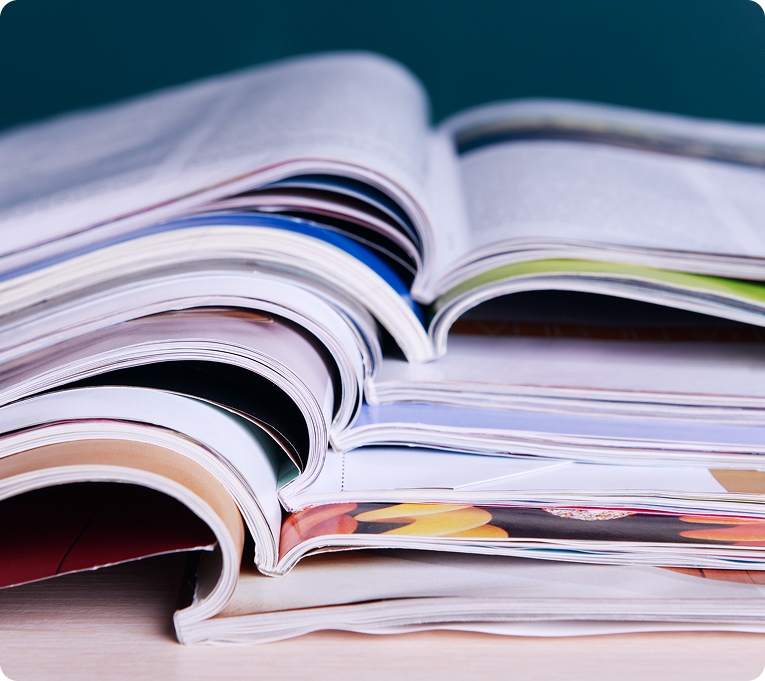 Stack of open magazines or reports showing printed pages with colorful charts and graphics.