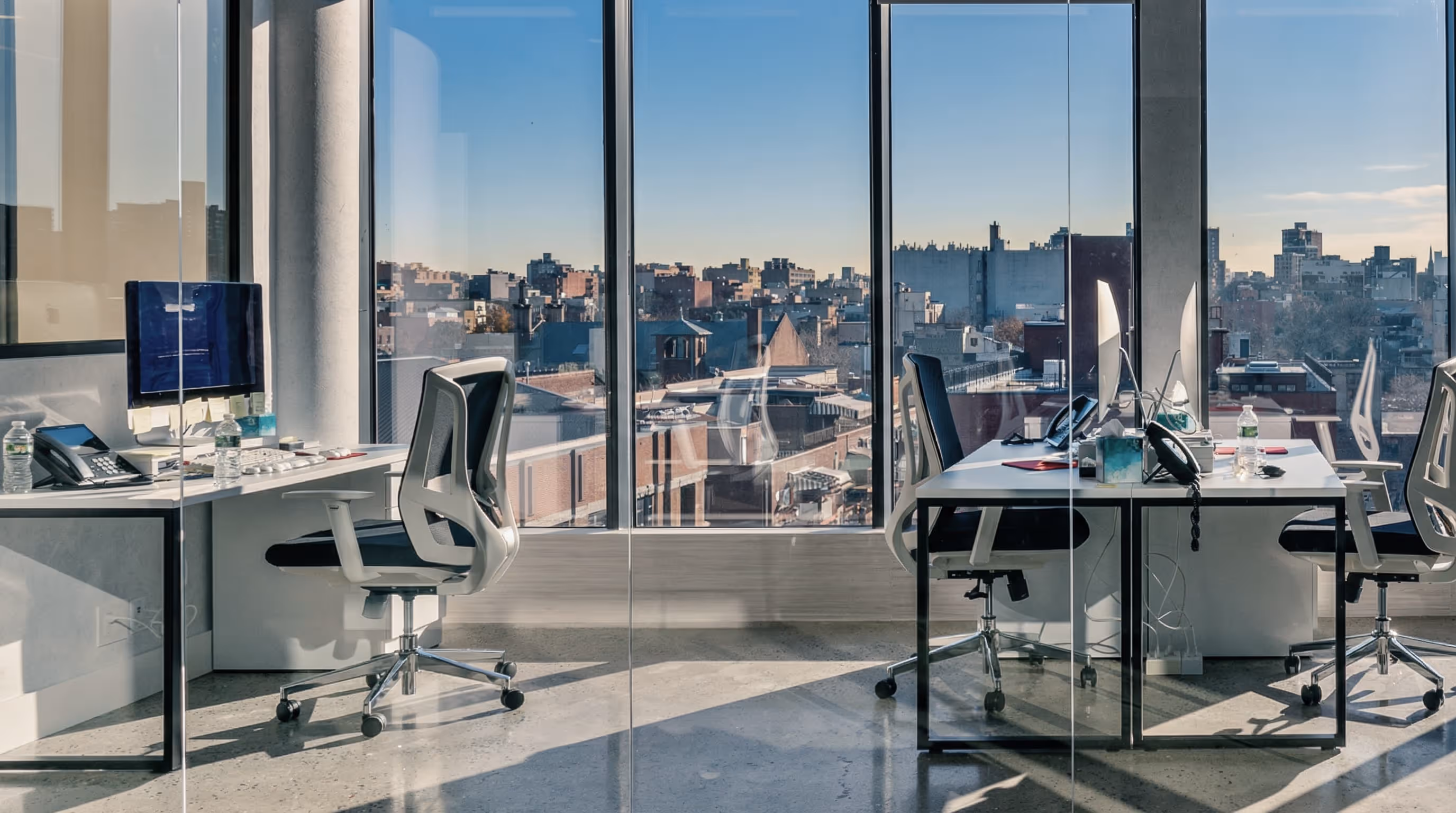 Modern conference room with beige high-back chairs around a long table and a screen displaying 'Where Williamsburg Works' and a large 'W'.