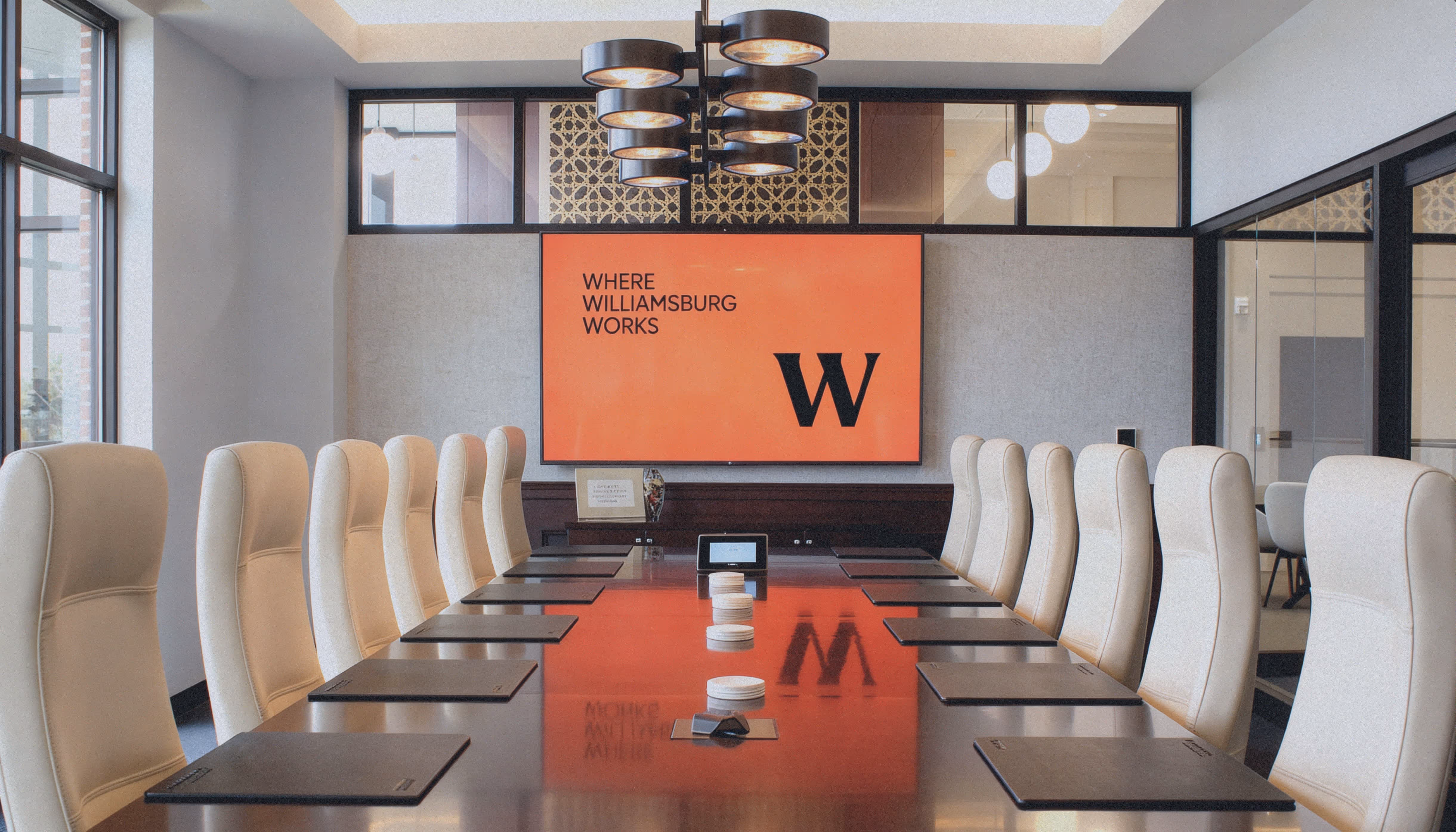 Modern office with ergonomic chairs, workstations, computers, telephones, and large windows overlooking a city skyline.