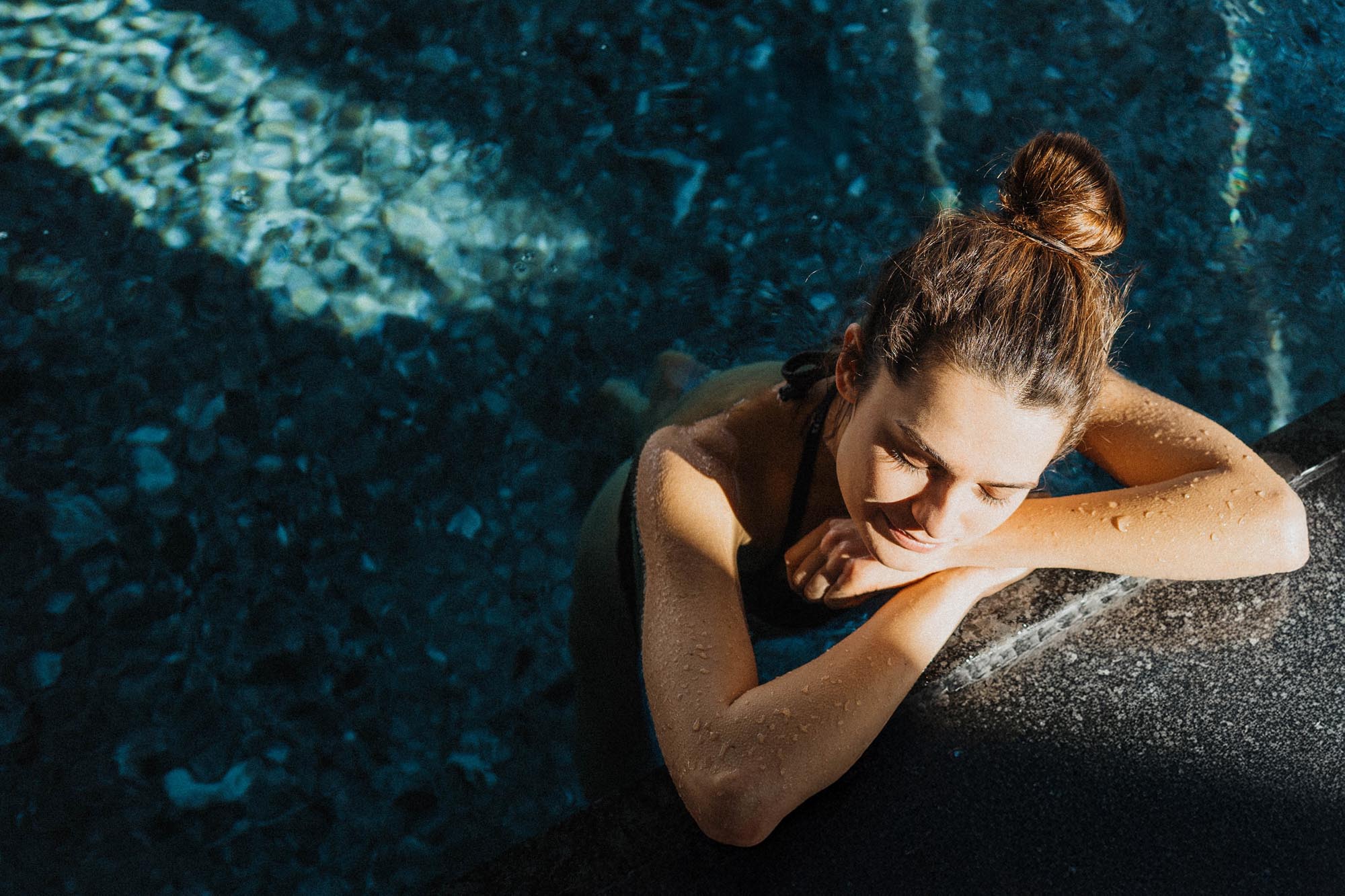woman relaxing by pool edge in sunlight