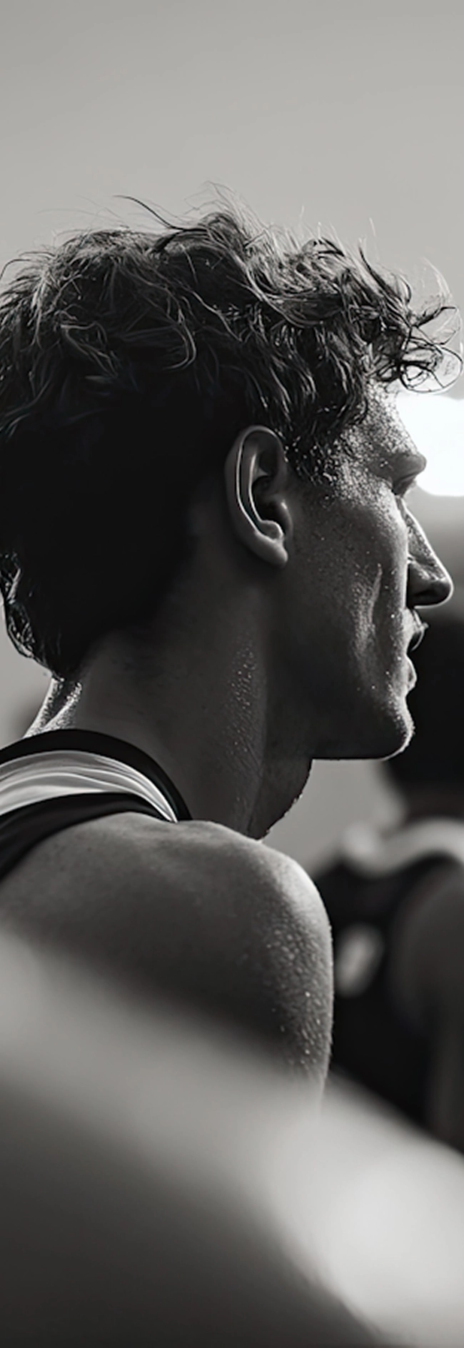 A man wearing a black tank top stands confidently, showcasing a casual and athletic style.