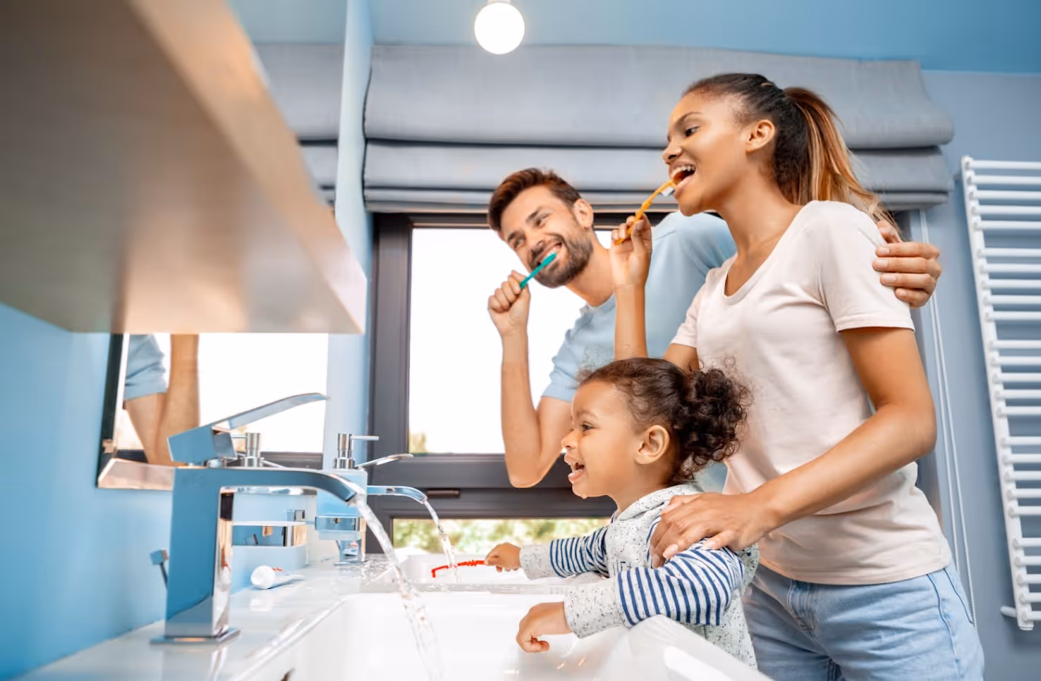 Family brushing their teeth together in front of a bathroom mirror