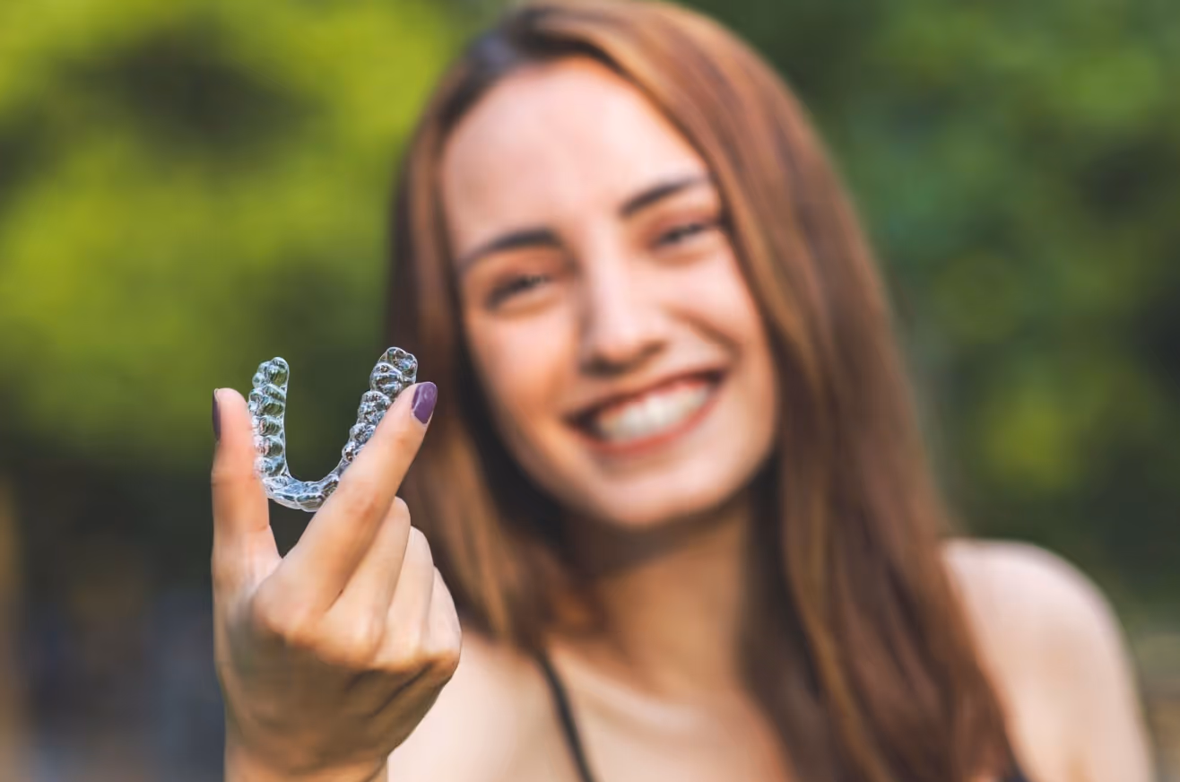 Close up shot of clear aligners with blurred out background of a girl smiling