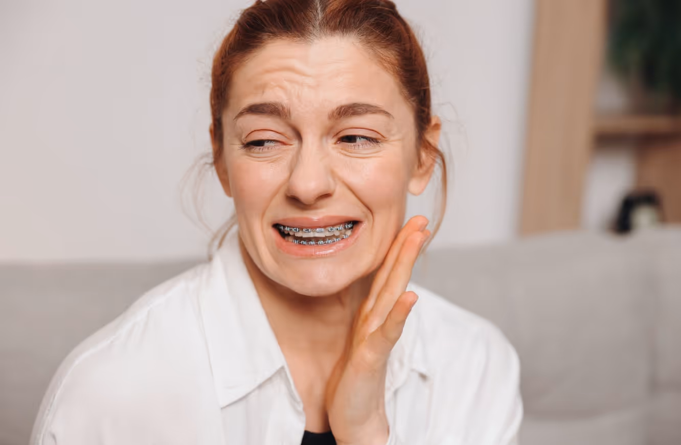 Woman with braces is in pain due to tight metal wires