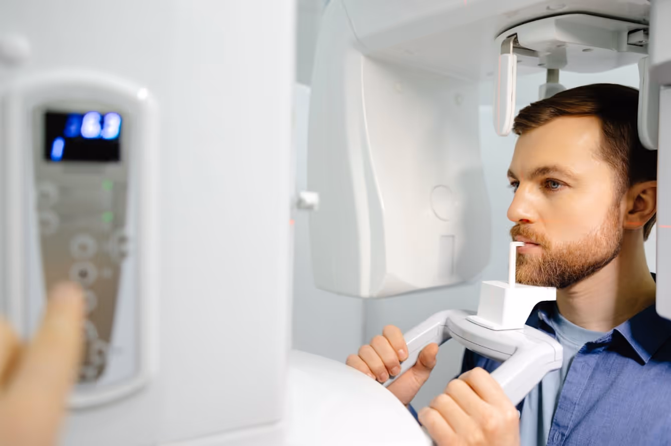 Man standing in a panoramic dental X-ray machine during imaging