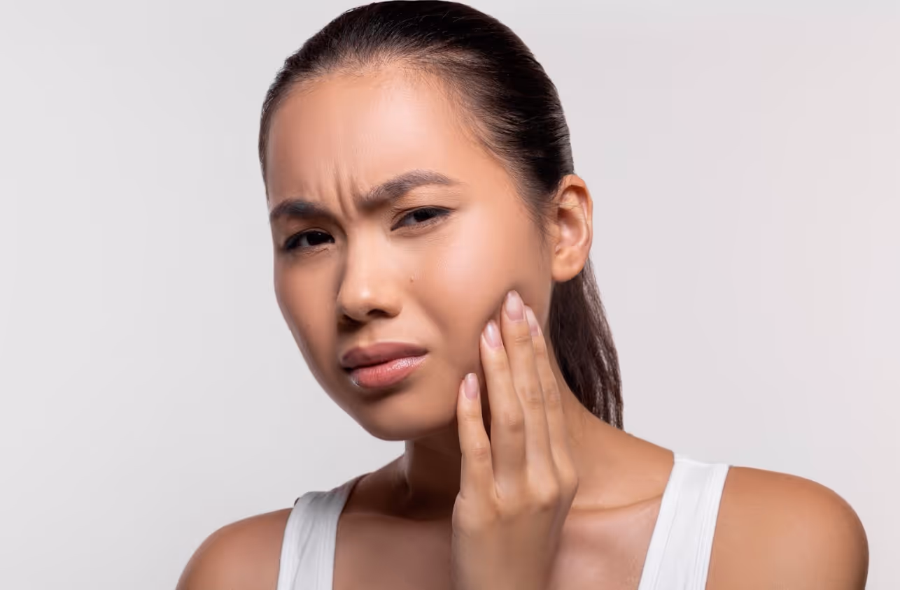 Woman touching her cheek and wincing from tooth pain