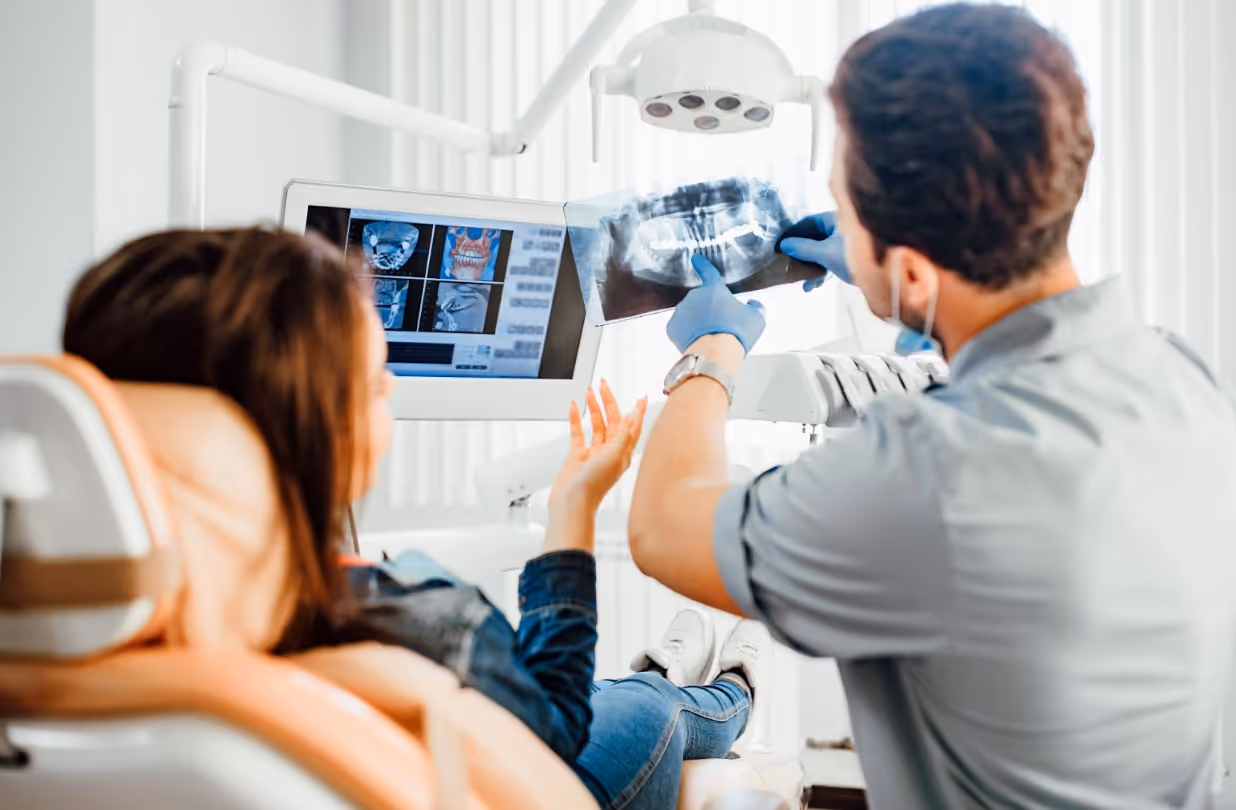 Dentist reviewing a dental X-ray with a patient during an exam.