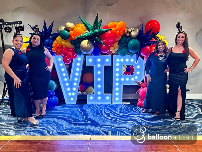 Light up marquee letter and number sign rentals with balloon arch decoration around it for a photo moment at a company event.