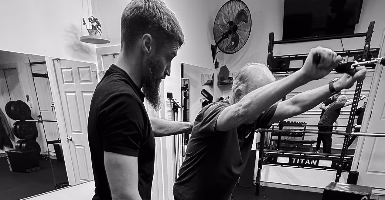 Personal trainer assisting an older adult with an upper body mobility exercise during a one on one personal training session in Vancouver, Washington.