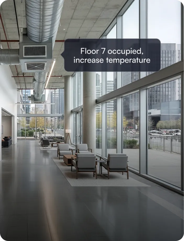 Modern office lobby with large windows, seating area, and airflow duct, displaying message 'Floor 7 occupied, increase temperature.'