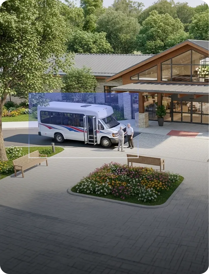 Two elderly men standing and talking near a white shuttle bus parked outside a modern building surrounded by trees and flower beds.