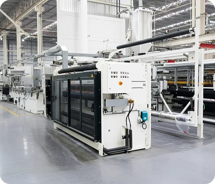 Industrial manufacturing machine with control panel in a spacious factory setting.