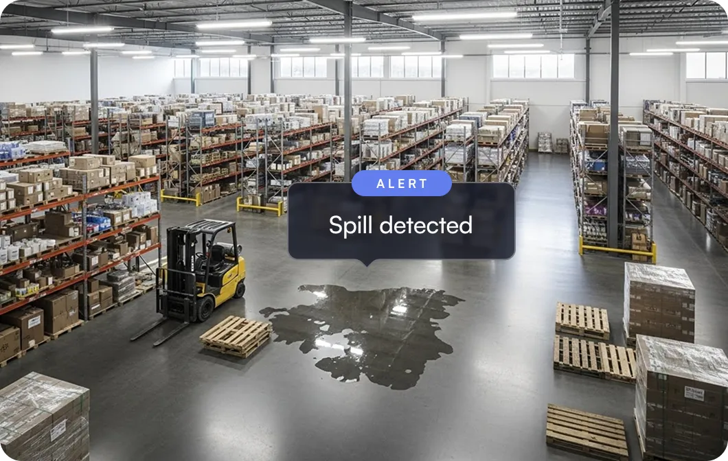 Warehouse interior with shelves stocked with boxes, a forklift near a large liquid spill on the floor marked by an alert sign reading 'Spill detected'.