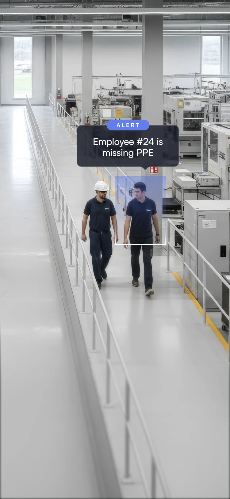 Two factory workers walking inside a manufacturing plant, one wearing a helmet and the other missing PPE with an alert warning.
