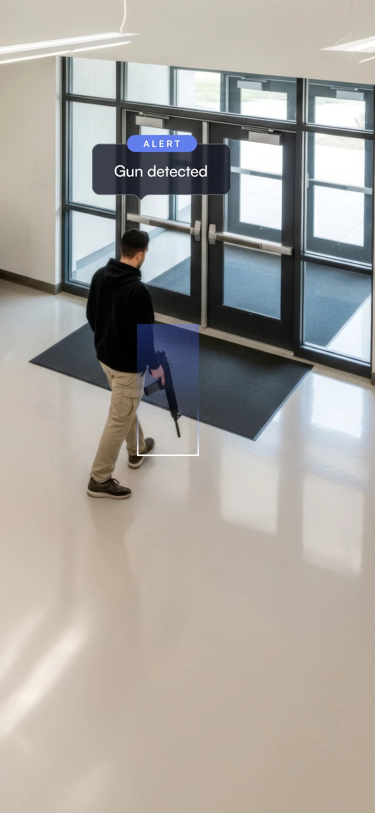 Man holding a gun near glass exit doors with an alert message saying 'Gun detected'.