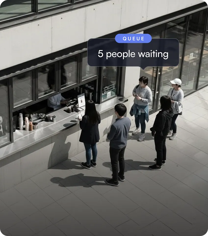 Five people standing in a queue outside a service window of a modern building.