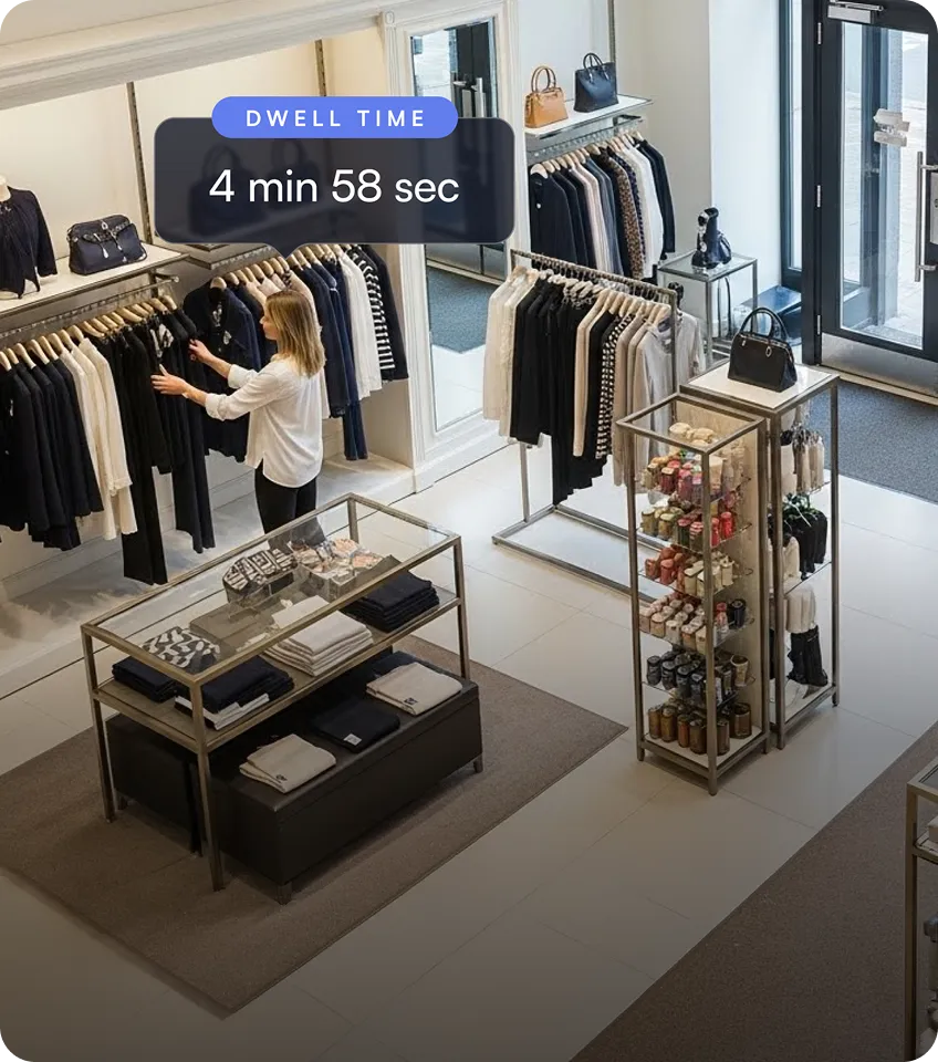 Woman browsing black and white clothing on racks in a bright, modern boutique with shelves displaying handbags and accessories.
