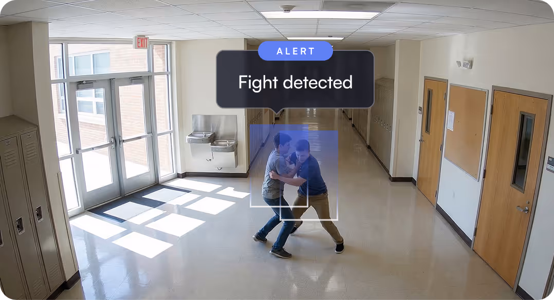 Two boys engaged in a physical fight in a school hallway with an alert saying 'Fight detected'.