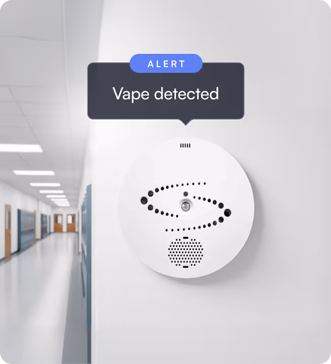 Wall-mounted vape detector with an alert notification displaying 'Vape detected' in a school hallway.