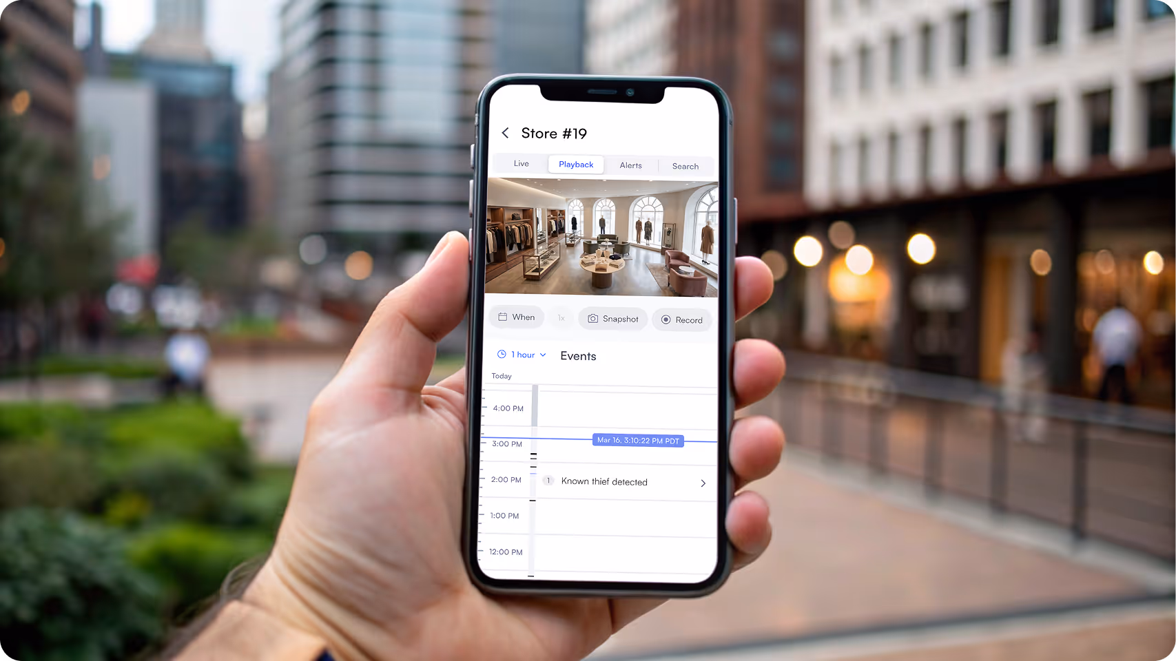 Hand holding smartphone displaying retail store surveillance app detecting a known thief event at Store #19.