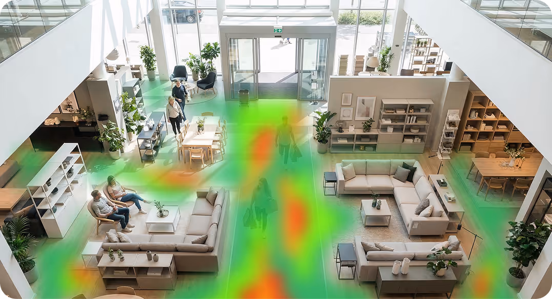 Modern furniture showroom with sofas, dining tables, shelves, plants, and customers walking around and sitting.